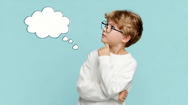 Thoughtful boy in glasses looking at empty speech bubble on blue background with hand on chin thinking