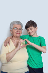 Grandma and grandson making heart gesture with hands – intergenerational love, family bonding, emotional connection, happy childhood, senior care, support, trust, warm relationship, unity symbol.