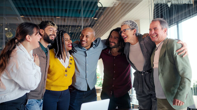 Professional team celebrating successful project milestone, sharing joyful moment of unity and laughing together in modern office workspace, highlighting collaborative workplace achievement