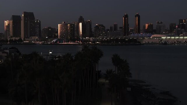 Aerial The Rady Shell By Illuminated Buildings In Modern City, Drone Flying Forward Over Bay At Night - San Diego, California