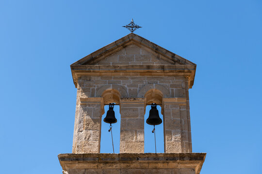 Church Dermatousa Bell Tower. Twin bells hang in the historic stone bell tower of Church Dermatousa in Zakynthos, Greece, under a clear blue sky.