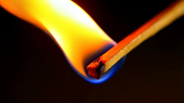 Burning matchstick with vibrant blue, yellow, and orange flame against a dark backdrop showing the initial ignition process.