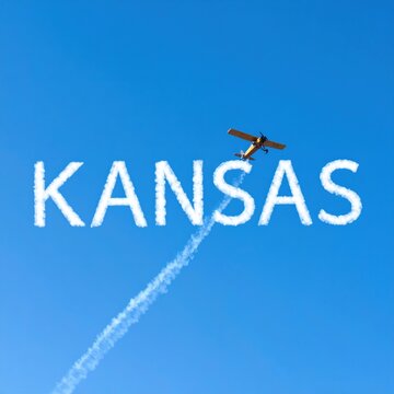 Yellow plane writing kansas in sky with cloud trails on a clear day