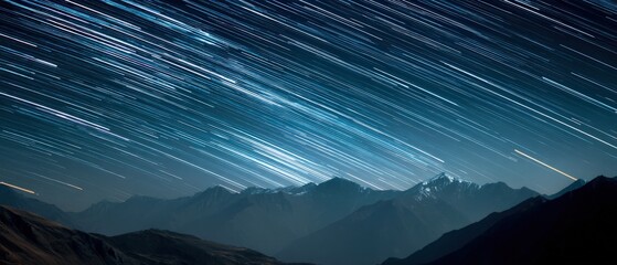 Majestic star trails streak across the night sky above a range of dark mountains. A breathtaking view of celestial movement.
