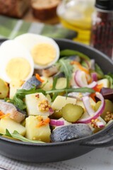 Delicious salad with herring, egg and vegetables in bowl on table, closeup
