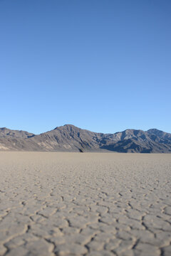 Racetrack Playa cracked dried lake bed with mountains and blue sky in Death Valley