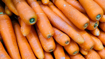 Fresh orange carrots stacked in a market display in vibrant colors for sale at local grocery store