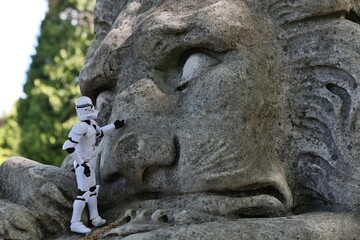 Naklejka premium Star Wars articulated action figure of Clone Trooper touching large stone statue of sleeping lion. 