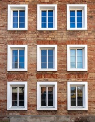 Fototapeta premium 古レンガ壁のテクスチャと白枠の正方形窓が織りなす美しい規則性のディテール。