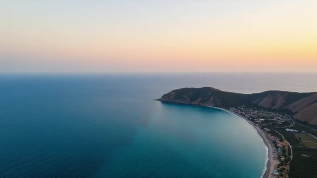 Drone view of the sea coast with blue water and hills at sunset