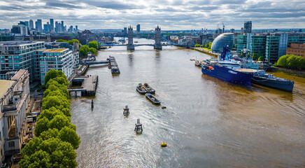 Moored ships on the River Thames near Tower Bridge and modern buildings on a cloudy day in London