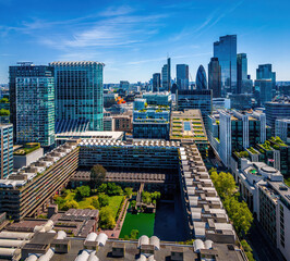 Colorful aerial view of London's Barbican Estate with high-rise buildings, modern architecture, and city skyline under a blue sky