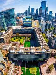 Colorful aerial view of London's Barbican Estate with high-rise buildings, modern architecture, and city skyline under a blue sky © Alexey Fedorenko