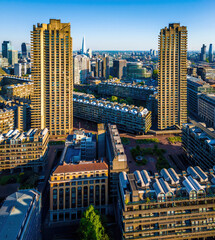 Colorful aerial view of London's Barbican Estate with high-rise buildings, modern architecture, and city skyline under a blue sky