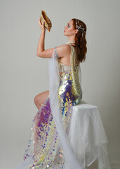 Fantasy studio portrait of a red-haired mermaid faery model wearing white pearl gown, fairytale...