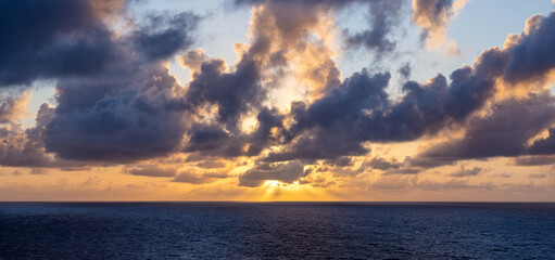 Dramatic Sunset Over Ocean with Luminous Clouds and Golden Sky