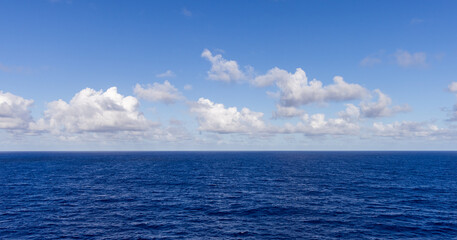 Serene Ocean View Under a Bright Blue Sky and Fluffy Clouds