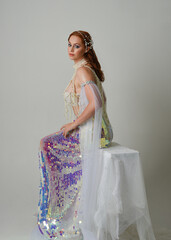 Fantasy studio portrait of a red-haired mermaid faery model wearing white pearl gown, fairytale...