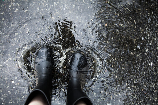 Feet stepping in pudle on road wearing gumboots