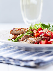 Fried pork tenderloin with tomato salsa. Bright background. Close up.	