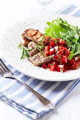 Fried pork tenderloin with tomato salsa. Bright background. Close up.	