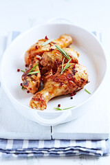 Spicy Chicken Drumsticks with fresh herbs. White wooden background	