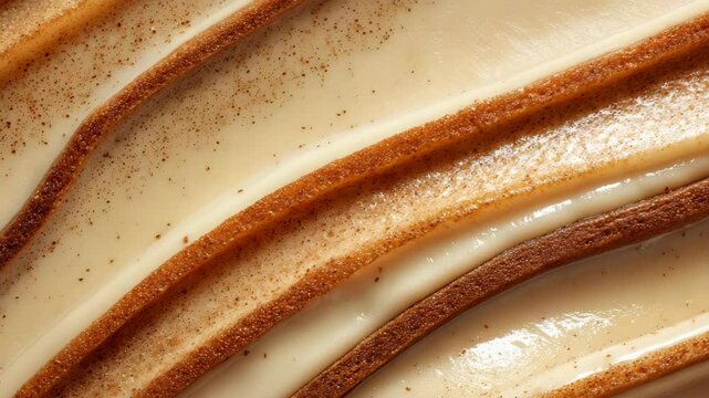 Creamy beige swirls with brown cinnamon specks, close up texture shot. Smooth, glossy surface.  Food photography background.