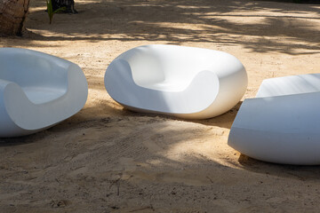 Comfortable white lounge chairs set on sandy beach surrounded by palm trees in a tropical paradise