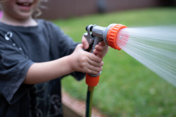 water hose with water sprinkler summer watering plants children playing with water outside