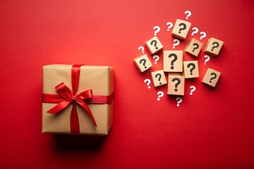 Unopened gift box with a red ribbon bow alongside question mark cubes on a red surface