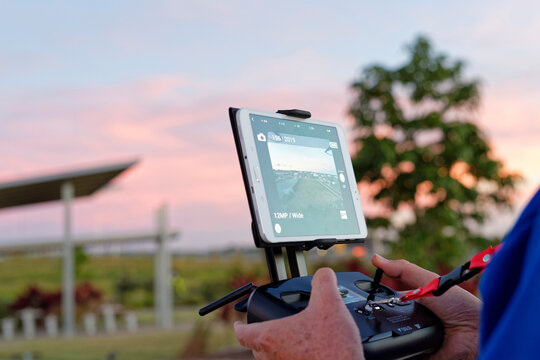 Man holding a controller watching flight path of drone at sunset