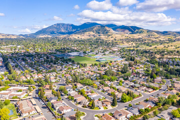 Aerial drone view of Concord, California, featuring residential neighborhoods, a sports complex, and Mount Diablo in the scenic background under a partly cloudy blue sky.