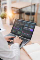 Business professional working on laptop with data analysis dashboard showing graphs and charts, modern office environment, focused and productive atmosphere