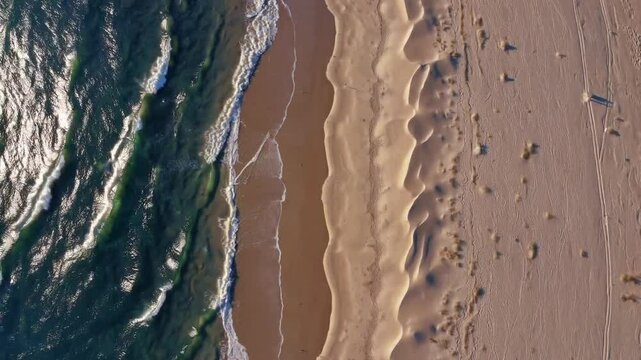 aerial view of a beach with waves crashing on the sandy shore, creating a beautiful natural scene
