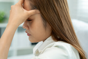 Fototapeta premium Headache, female having migraine pain, bad health, Asian woman feeling stress and headache, Office syndrome, sad tired touching forehead having migraine or depression, irritated girl, sadness grief