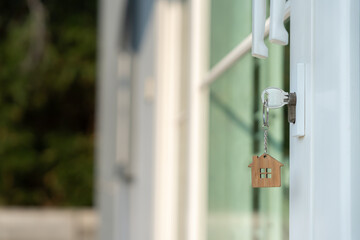 Landlord key for unlocking house is plugged into the door. Second hand house for rent and sale. keychain is blowing in the wind. mortgage for new home, buy, sell, renovate, investment, owner, estate..
