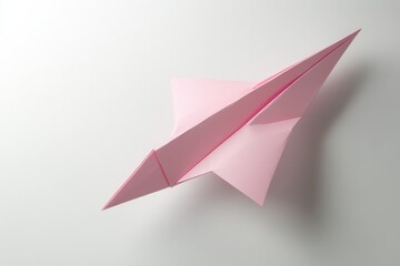 Fototapeta premium Pink paper airplane on white background