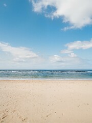 Fototapeta premium A beach is seen with waves of water and clouds in view.