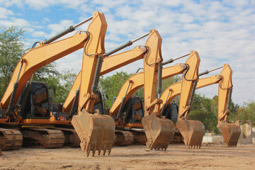 Lots of excavators parked on construction area of industrial building in construction site under the blue sky background.Earthmoving construction equipment
