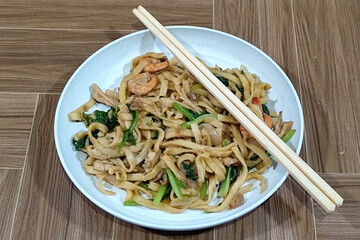 Fried noodles with vegetables and shrimp, looks very delicious served on a plate.