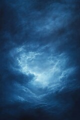 Fototapeta premium Dramatic deep blue cloudy sky with a bright light breaking through the dense layers of clouds, evoking a sense of mystery and awe