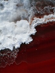 A strange red substance is covered in white foam.