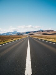 A straight road through grassland with mountains in background.