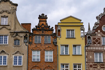Fototapeta premium fragment of historic townhouse facades in Gdańsk, showcasing a variety of architectural styles and vibrant facade colors. The buildings include richly decorated, brick, and plastered structures, creat