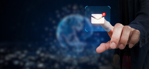 In a futuristic digital interface, a person's fingertip interacts with a glowing digital email icon, subtly set against the backdrop of a global network. This modern visual.