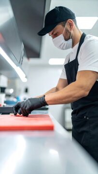 Chef wearing protective mask and gloves preparing food in restaurant kitchen