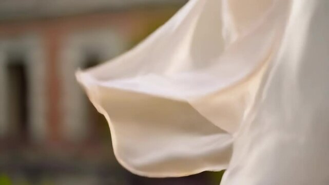 Elegant creamy white silk fabric gently flowing in a soft, natural light with subtle shadows, showing delicate folds and textures creating a luxurious atmosphere