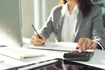 Doing finance, budgeting and tax calculation. Business woman hand using calculator to calculate financial report, accounting with laptop computer on table, budget management