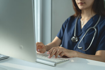 Female doctor working on laptop computer at doctor's office. writing prescripstion, recording patient's information, healthcare and medicine concept
