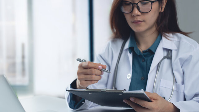Closeup, female doctor filling medical chart, checklist document, patient's information on clipboard. Doctor writing, signing on health insurance document in hospital, healthcare and medicine concept